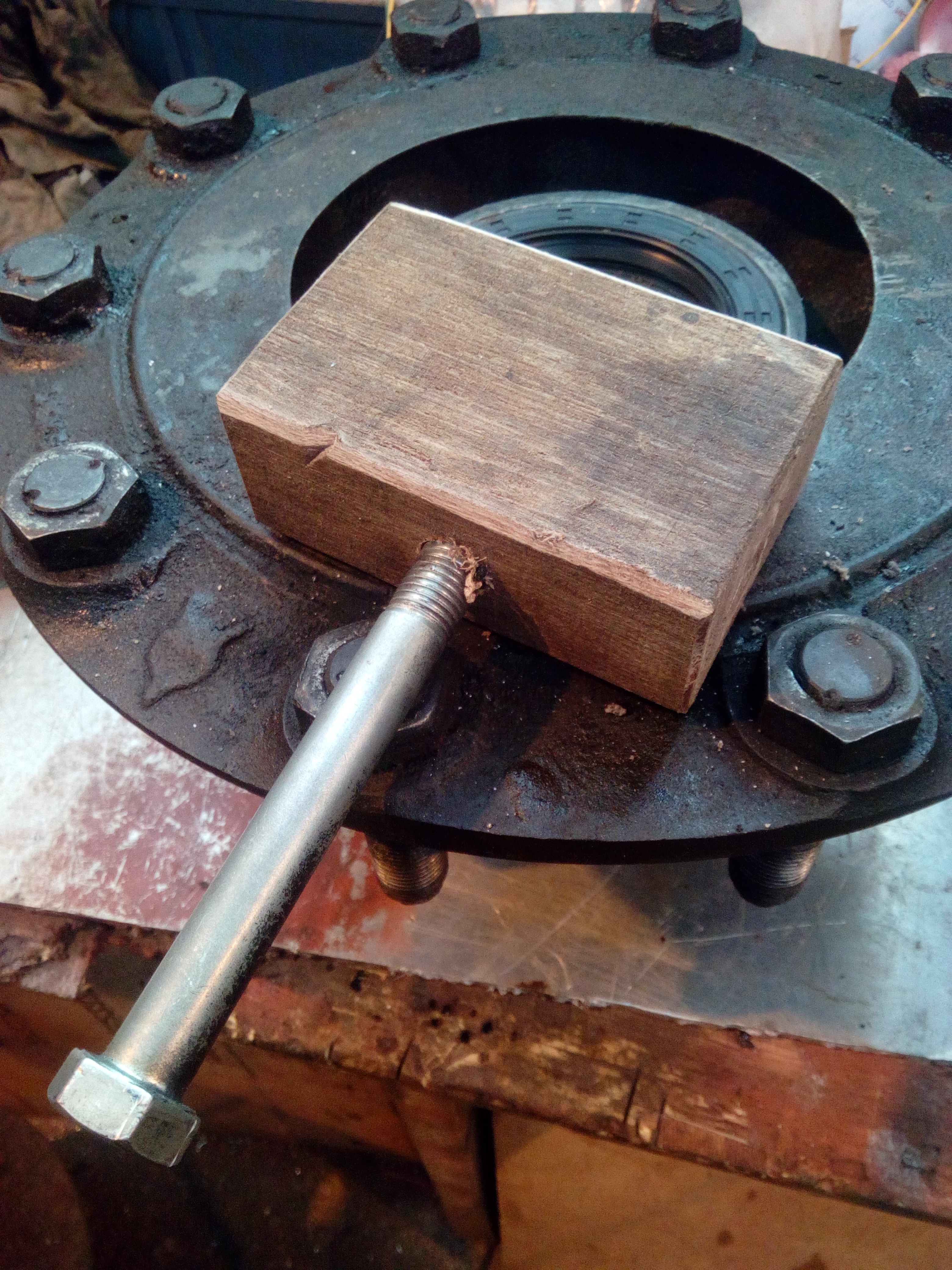 Hub upside down on the workbench, with a new seal in it. Laying
atop the hub is a crude wooden mallet made by screwing a large bolt
into a block of hardwood timber.