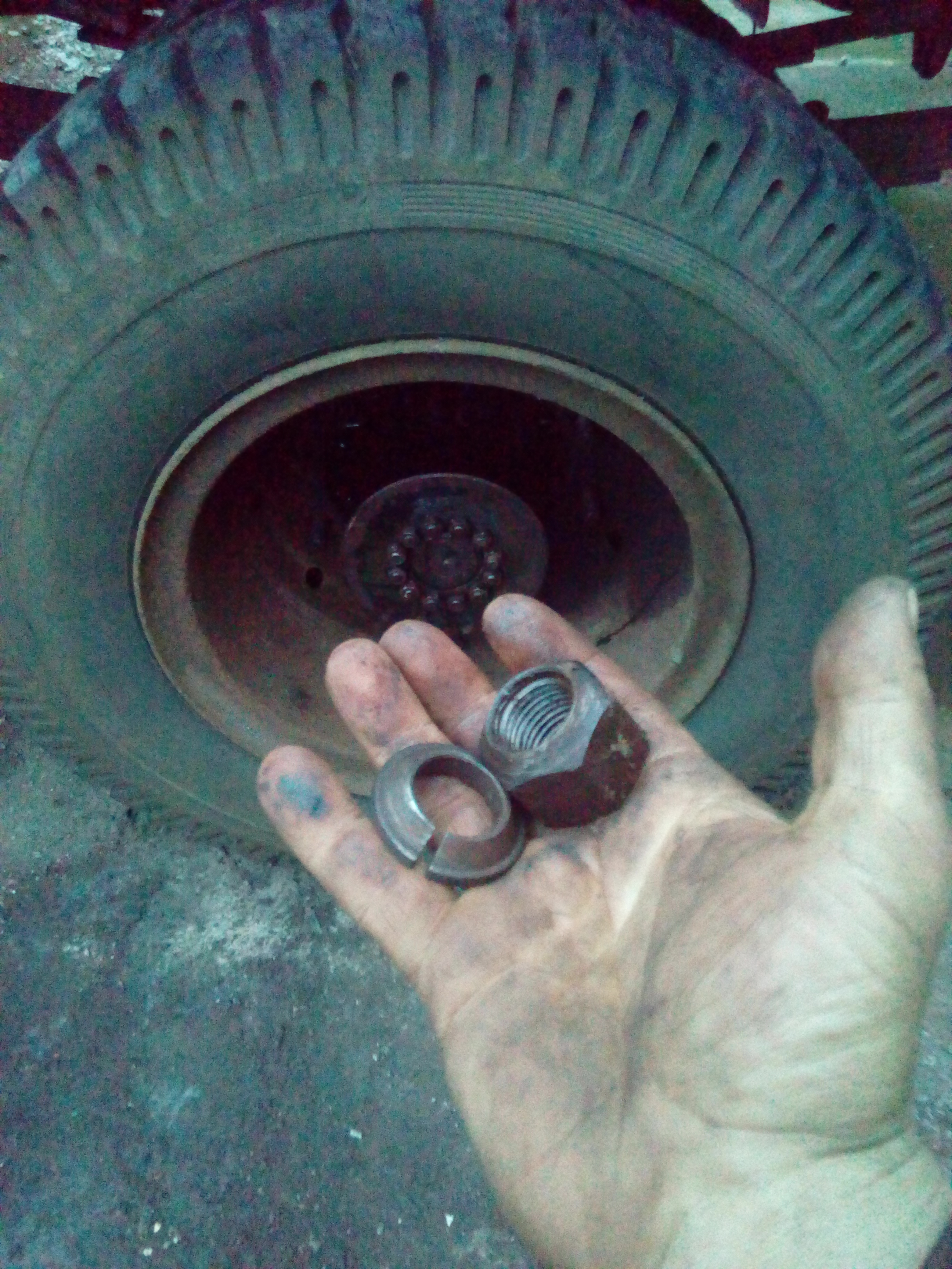 A hand holding a wheel-nut, and a tapered washer, in front of the
wheels that have been refitted to the hub.