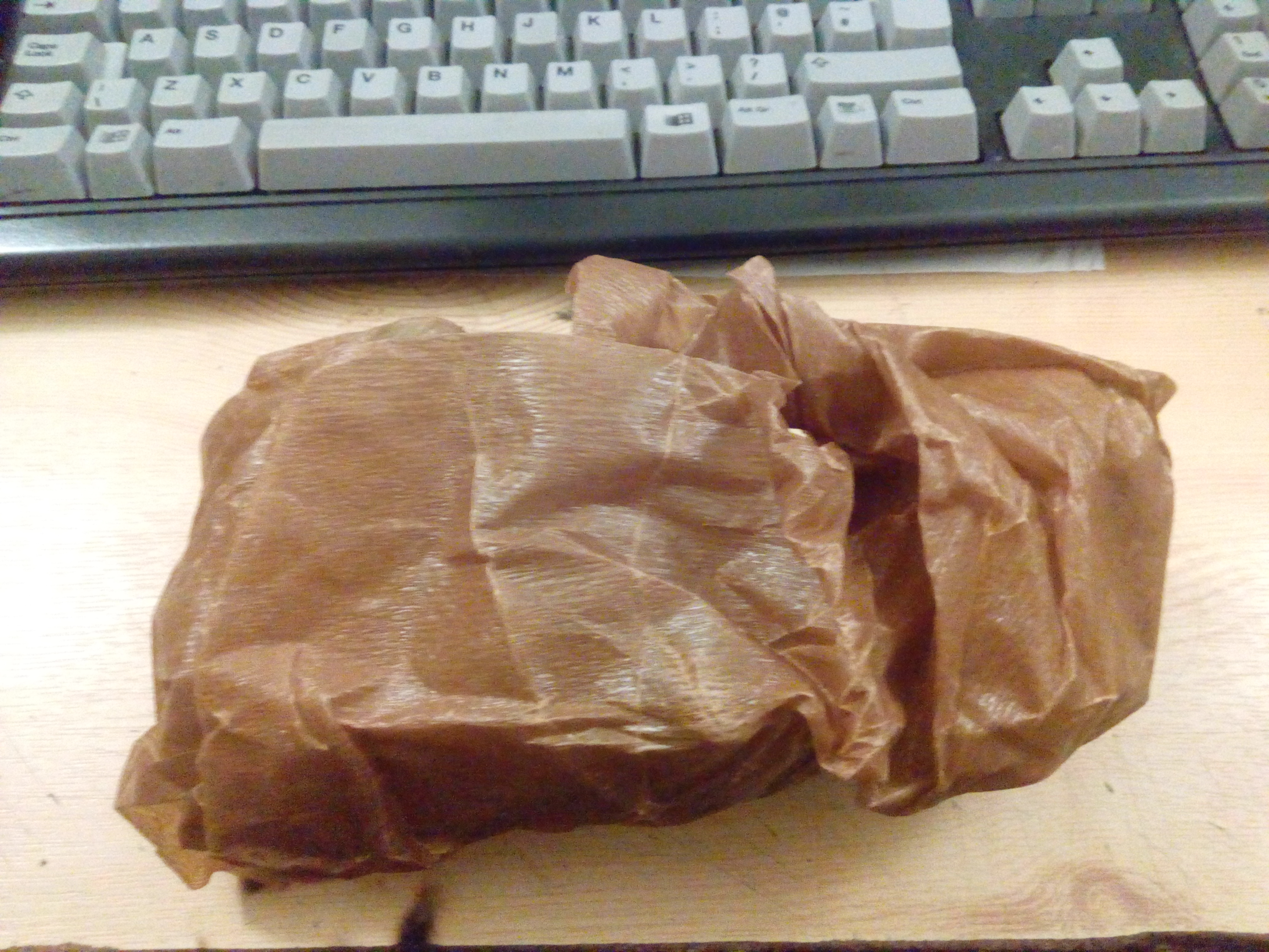 Photograph of an item wrapped in brown waxed anti-corrosion paper.