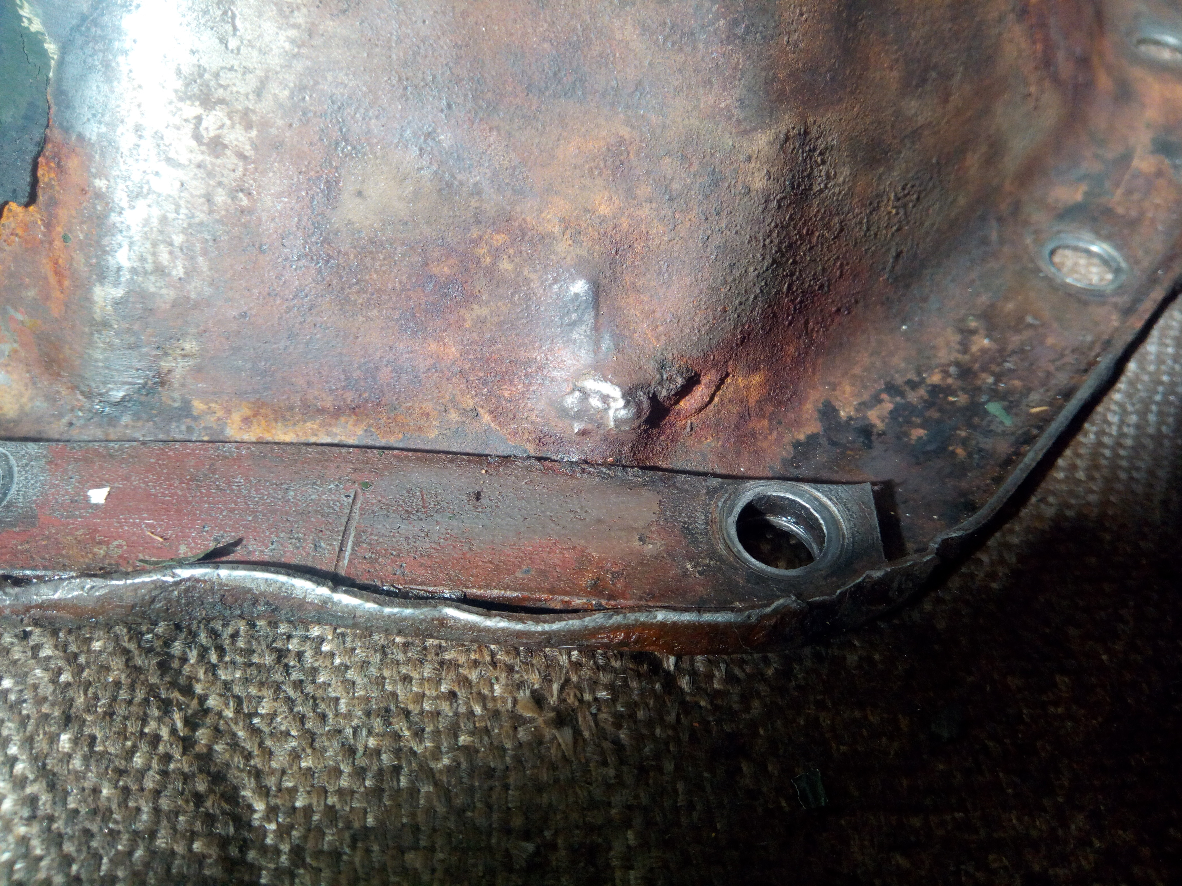 Repaired corner of the diff cover from the outside, with a
definite outwards lump, as if something has been driven into the cover
from the inside with significant force.