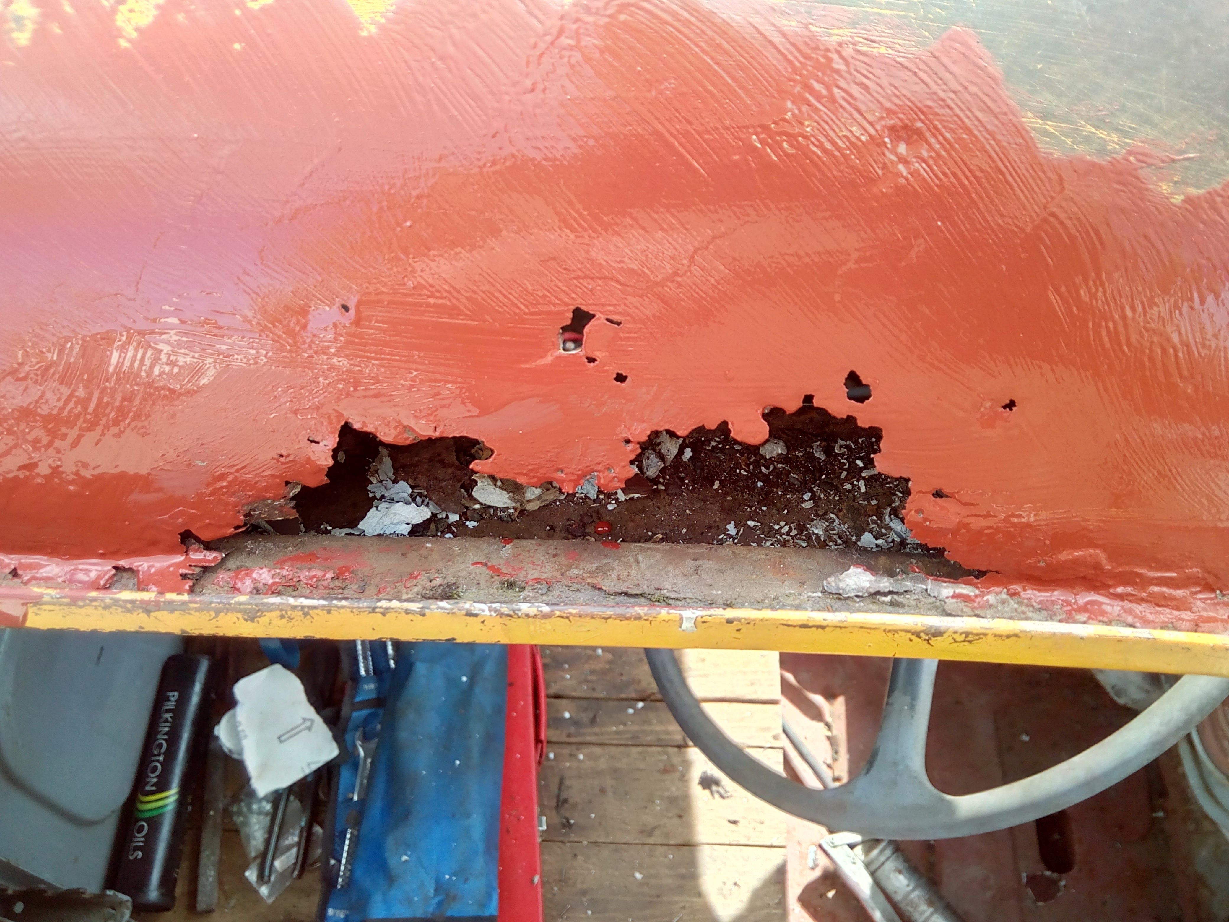 A ragged rusty hole in the truck roof, with bits of old
body-filler and newspaper visible through the hole; the roof has been
roughly painted with some brown-ish primer paint.