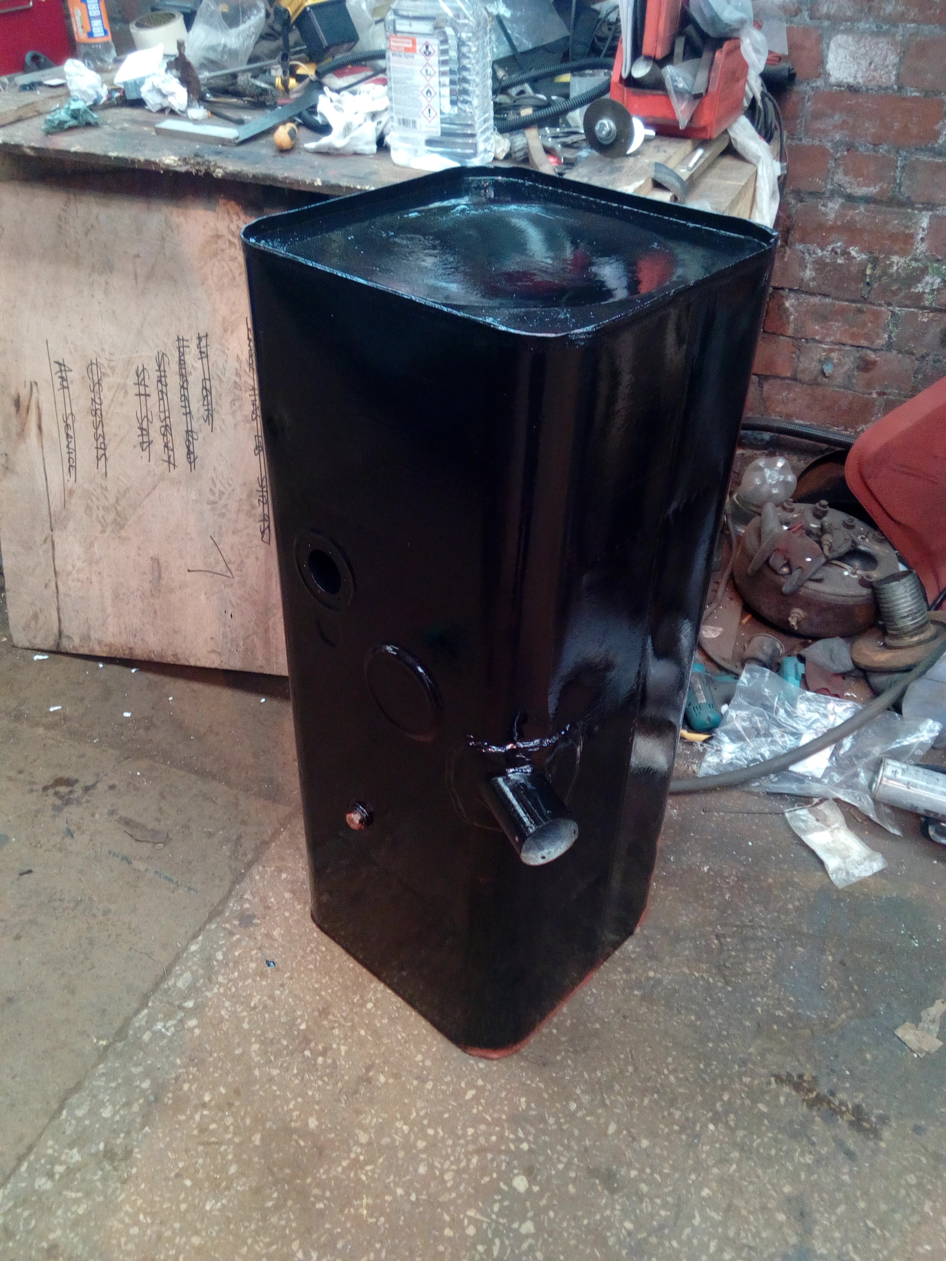 The same fuel tank, now painted in gloss-black paint. It's very shiny, and has visible brush-strokes.