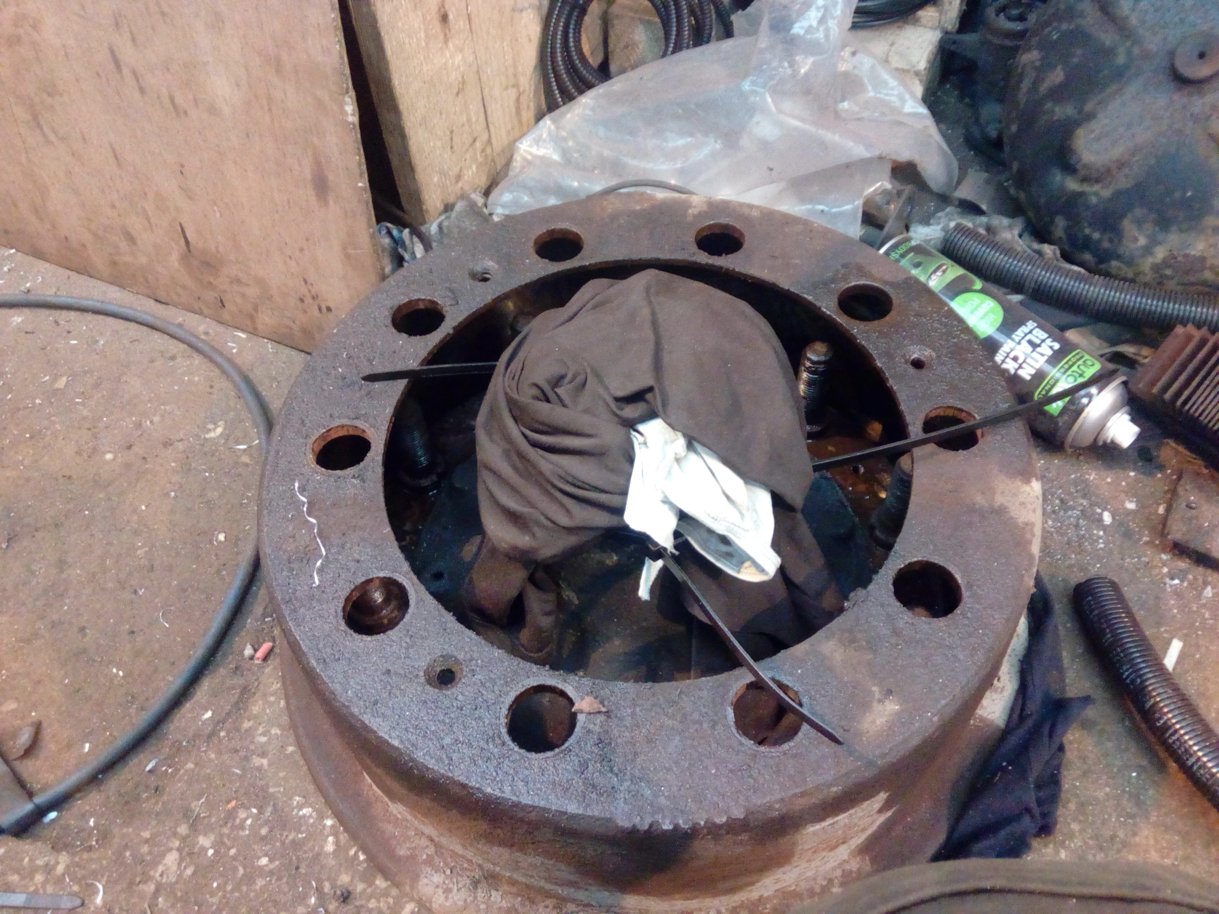 A brake drum on the workshop floor, with the hub dropped down
inside it, and the bearings protected by rags.