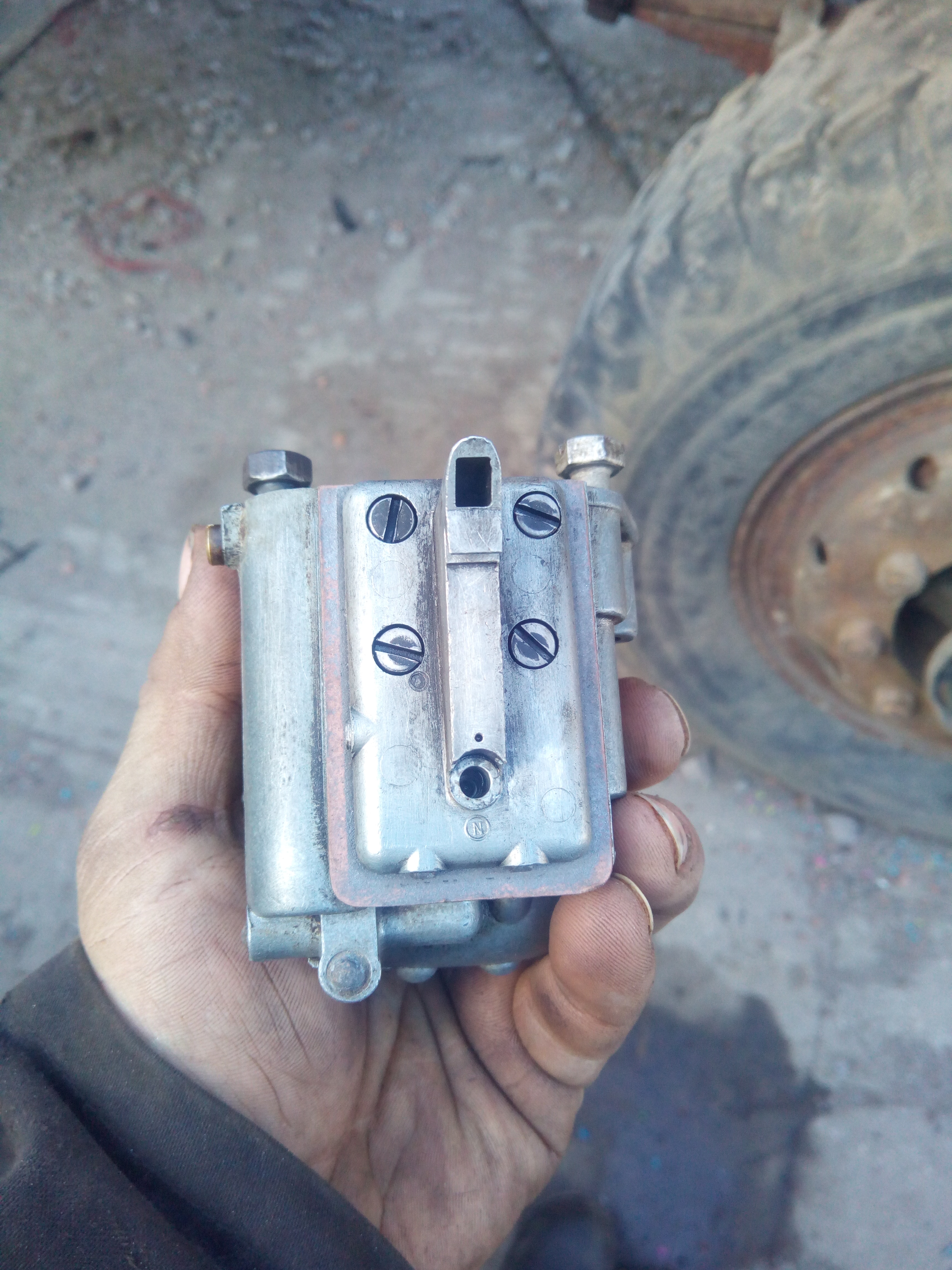 Same carburettor, with now only 4 screws in the metal plate. The
fifth screw, supposed to be in the bottom of the plate, beneath the
protrusion, is missing.