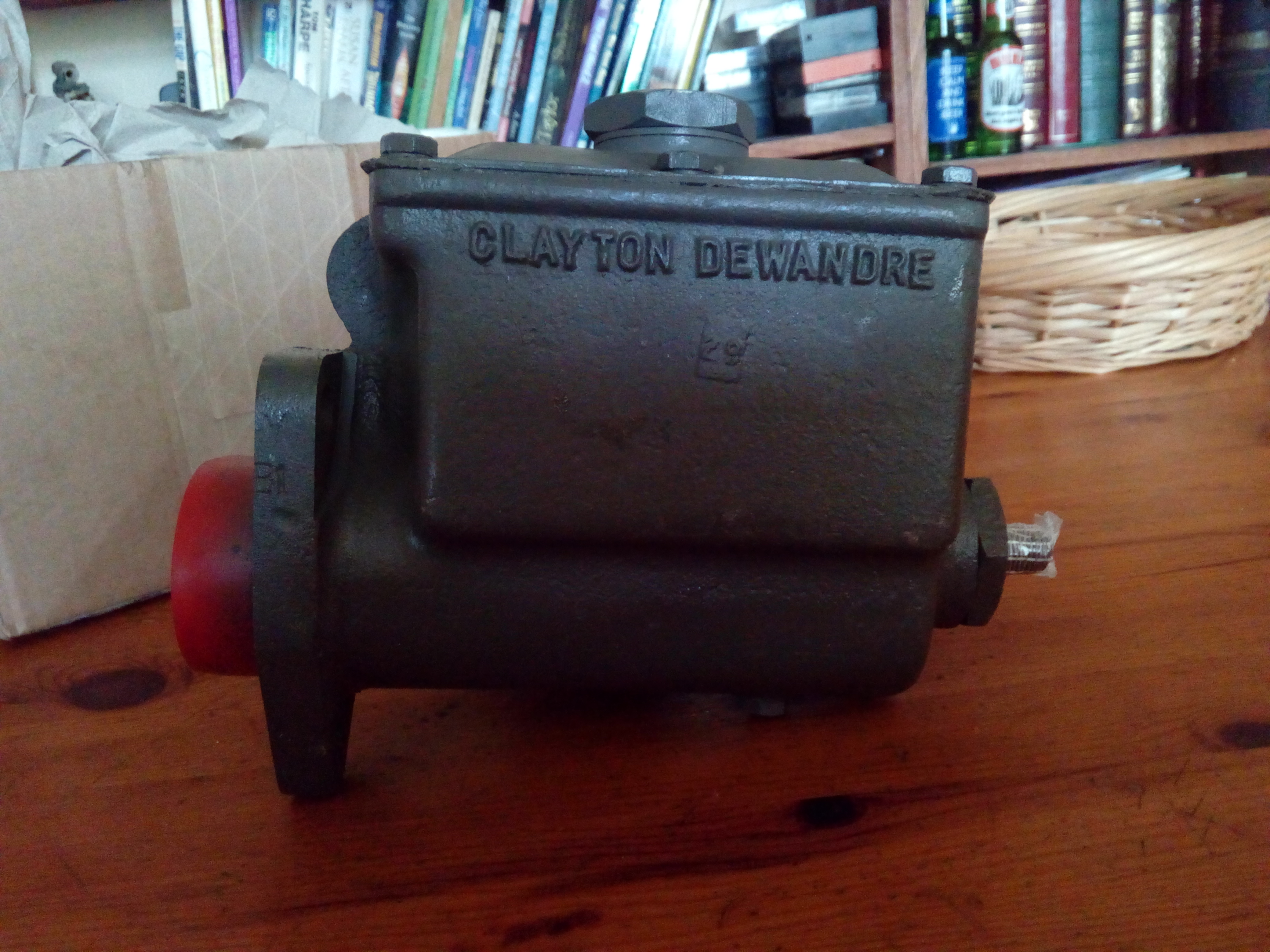 A grey-painted Clayton-Dewandre master cylinder sitting on a
wooden table. The ports are taped off.