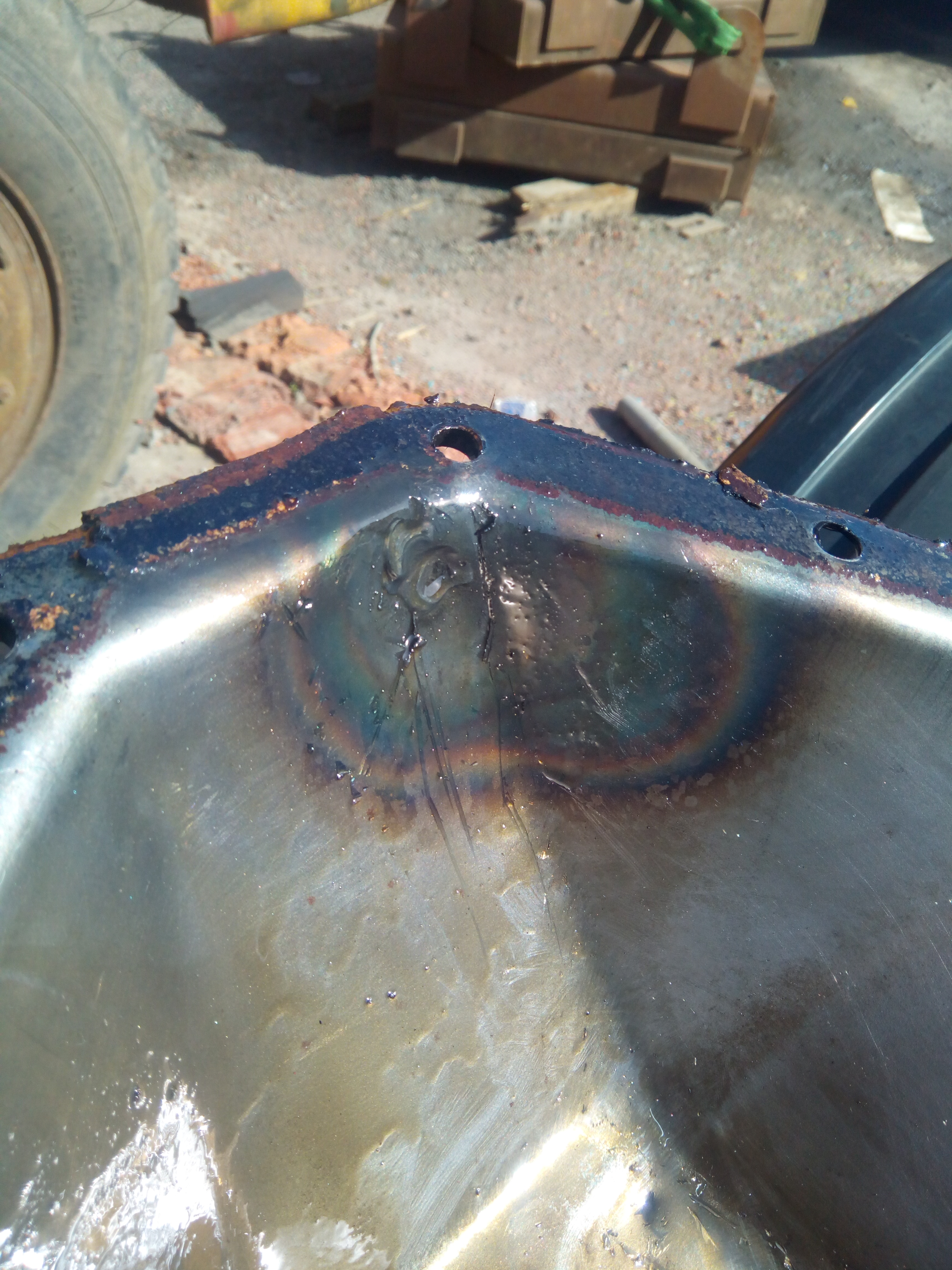 Inside of the diff cover, showing a corner that has previously
been welded to repair a hole; with a distinctive weld-puddle shape,
and a rainbow of heat-affected metal surrounding it.