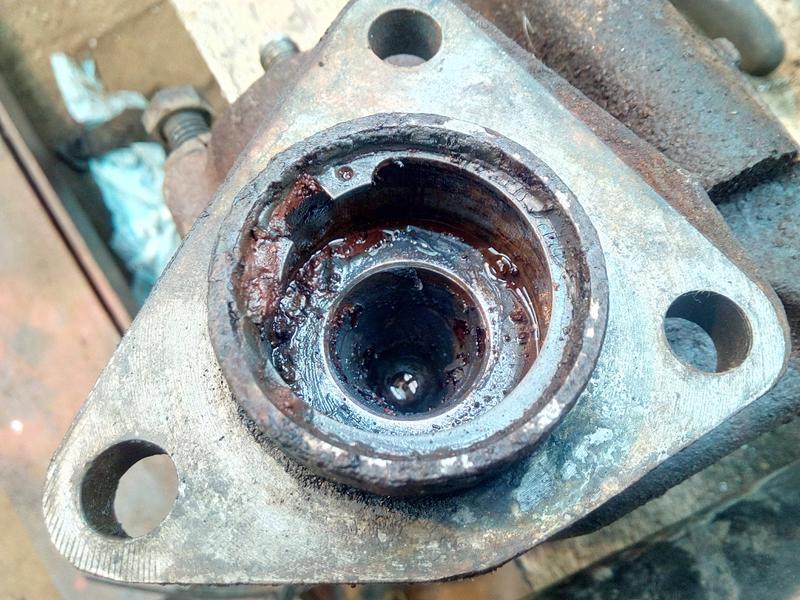 The same brake master cylinder, pictured from closer in, with the
rubber boot removed and exposing that the pistons inside the cylinder
are rusted in place and there is oily-looking rust clumps built up all
around the inside.