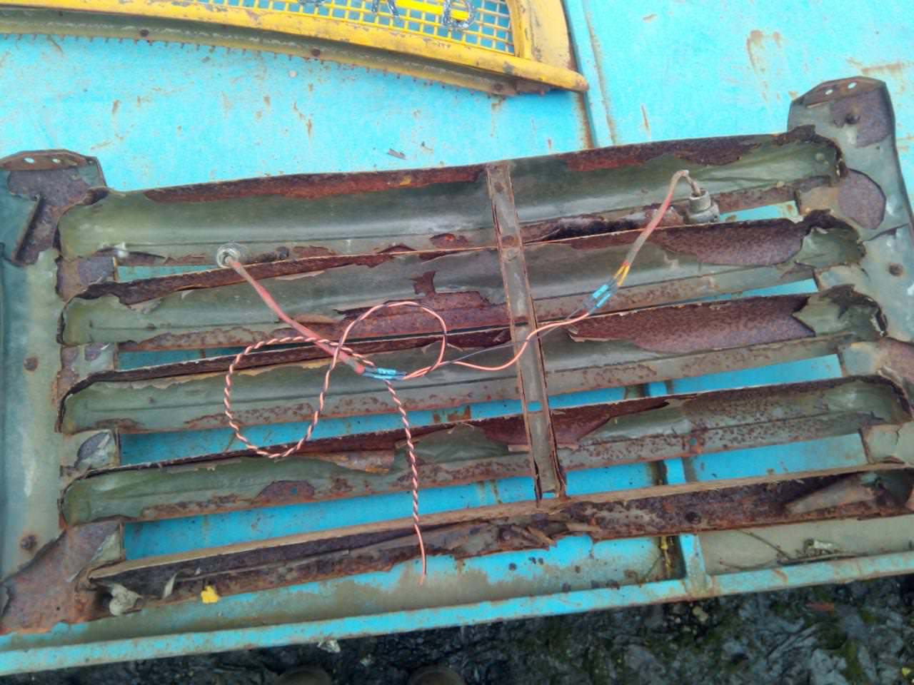 The grille removed and laid on a handy flat surface, showing the
peeling green paint from the truck's army days