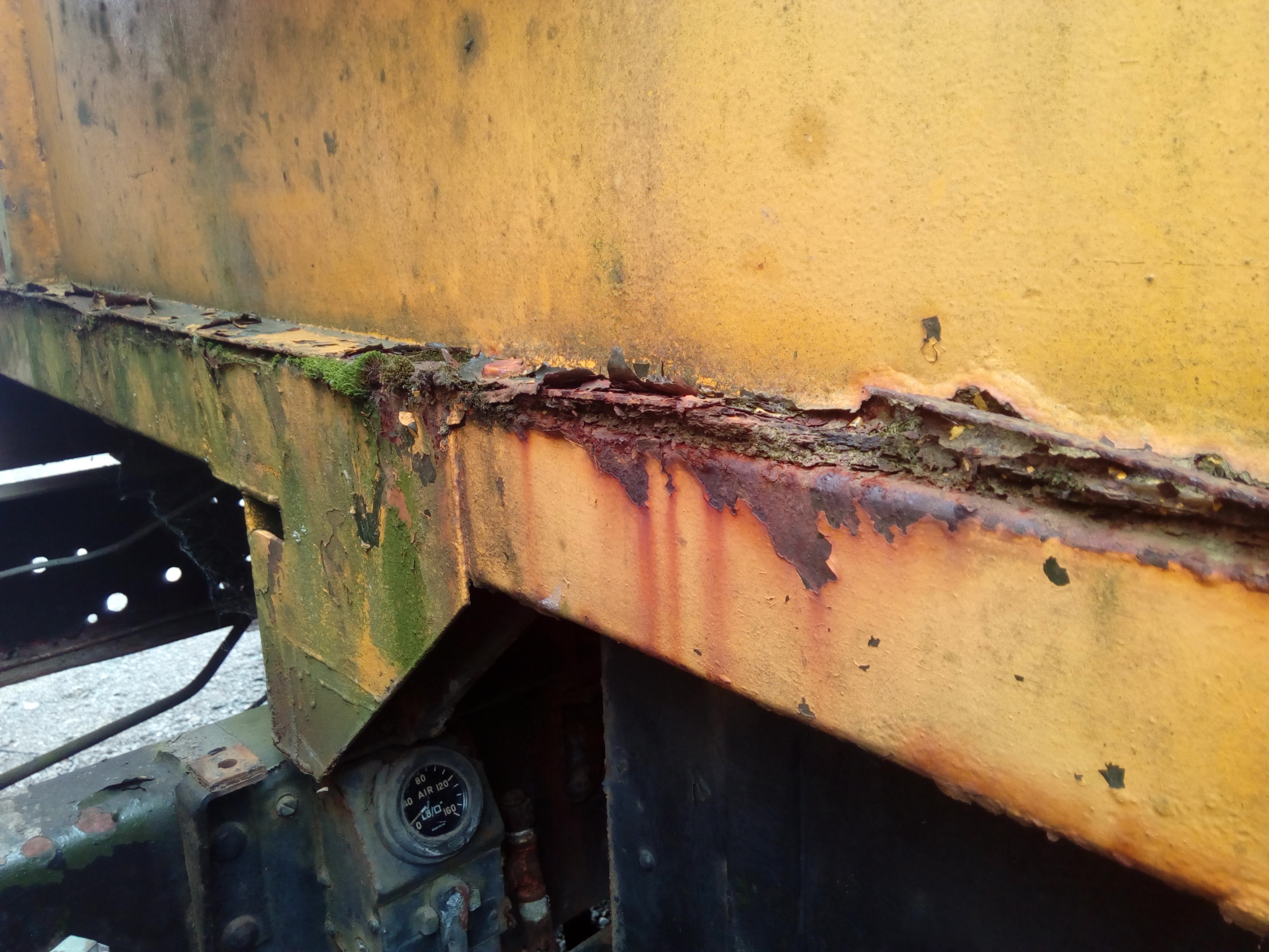 Photograph of the front of the truck body, closeup of flaked out paint and puffy rust in the metal.