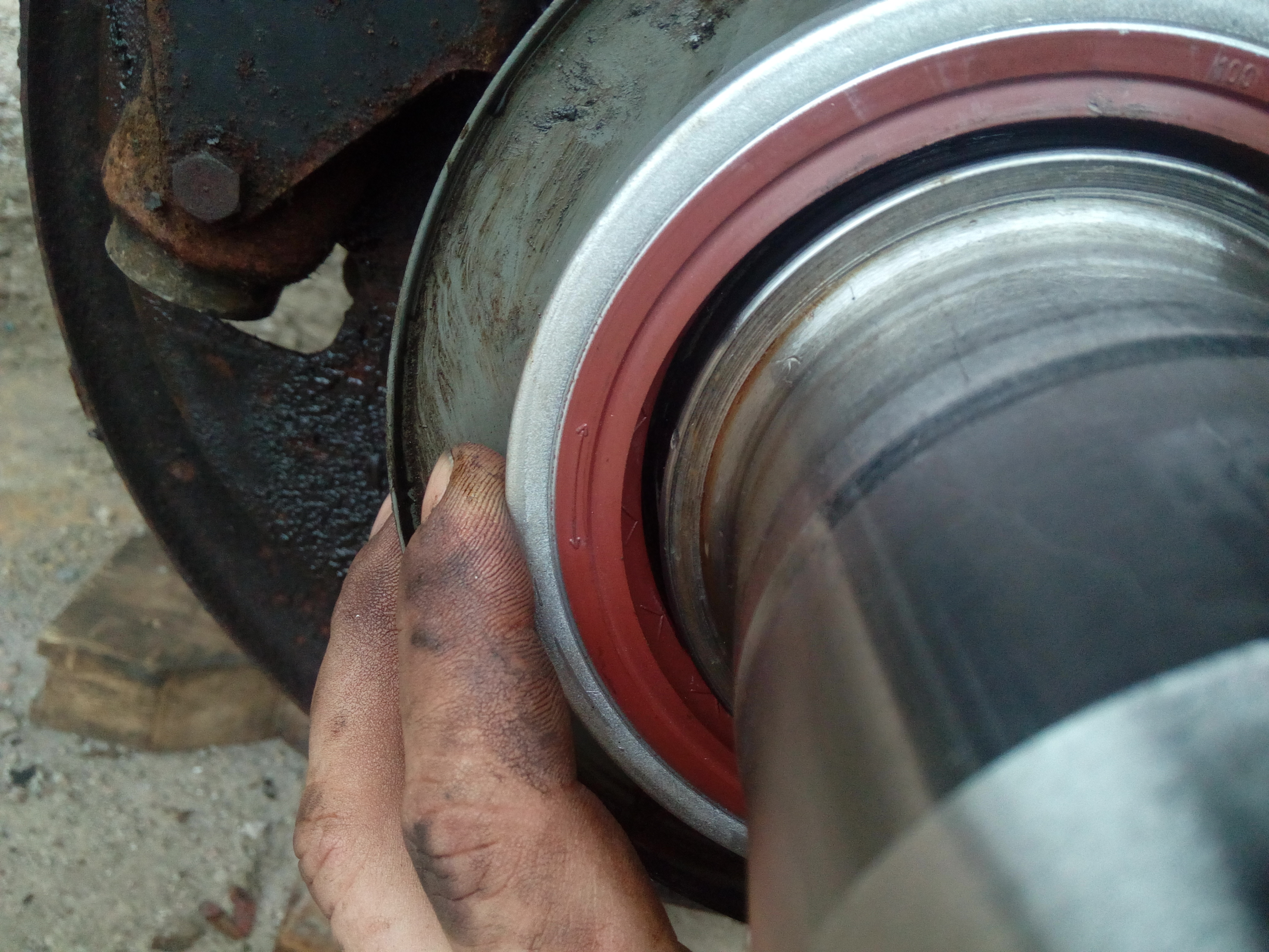 Close up of my hand holding a new axle seal onto the axle. The
seal is very much too big. By a lot.