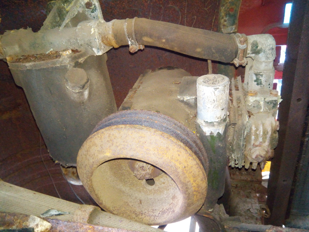 The air compressor and air-brake antifreeze reservoir,
photographed in their natural habitat: the rusty inside of the front
corner of the truck. The air compressor has a large rusty pully, and
an upright aluminium 'tower' that has rough grip marks on it like
someone has been trying to unscrew it.