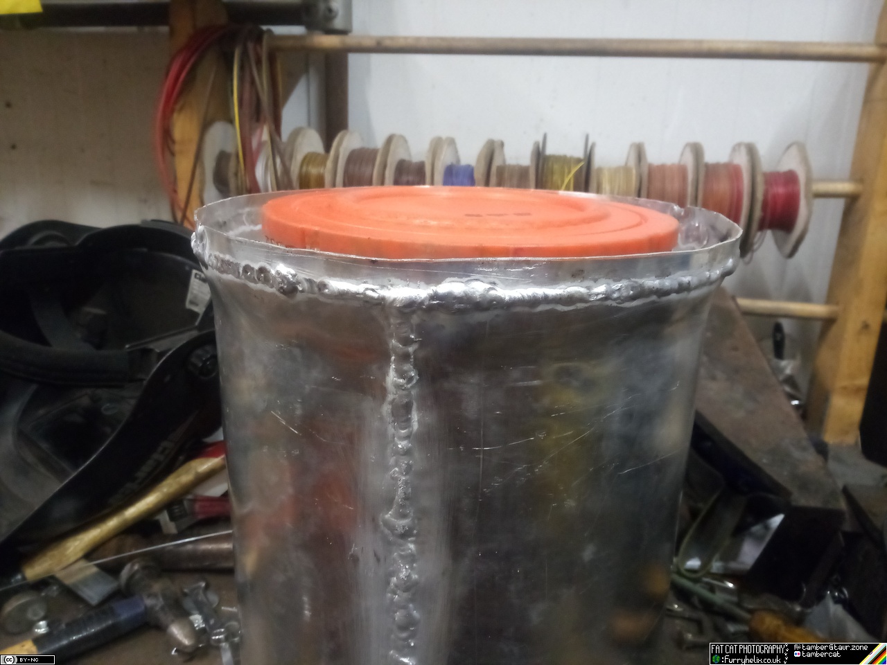 Shiny aluminium cylinder with an air filter sitting in it. The open upper edge of the cylinder has been extended upwards, with a visible weld seam.