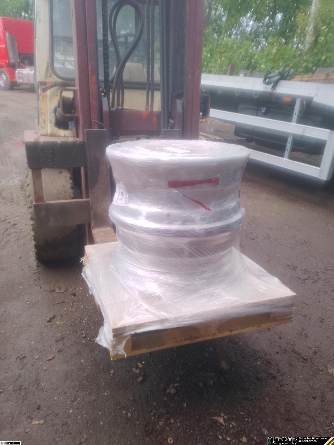 A pair of wheels, stacked on top of eachother on a pallet, all wrapped in shrink-wrap