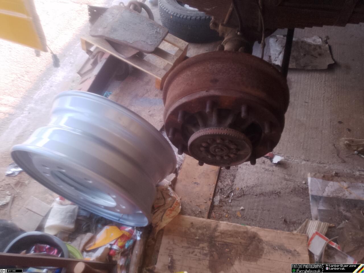 The modern wheel rim sitting on the floor beside the truck axle