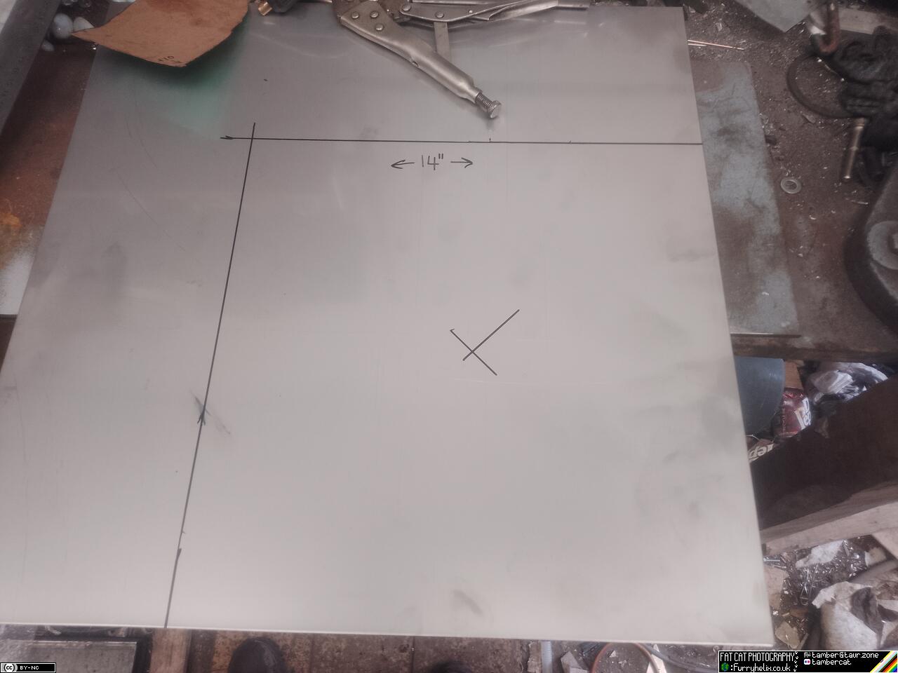 a sheet of stainless steel with a square marked out, along with the centre-point of that square