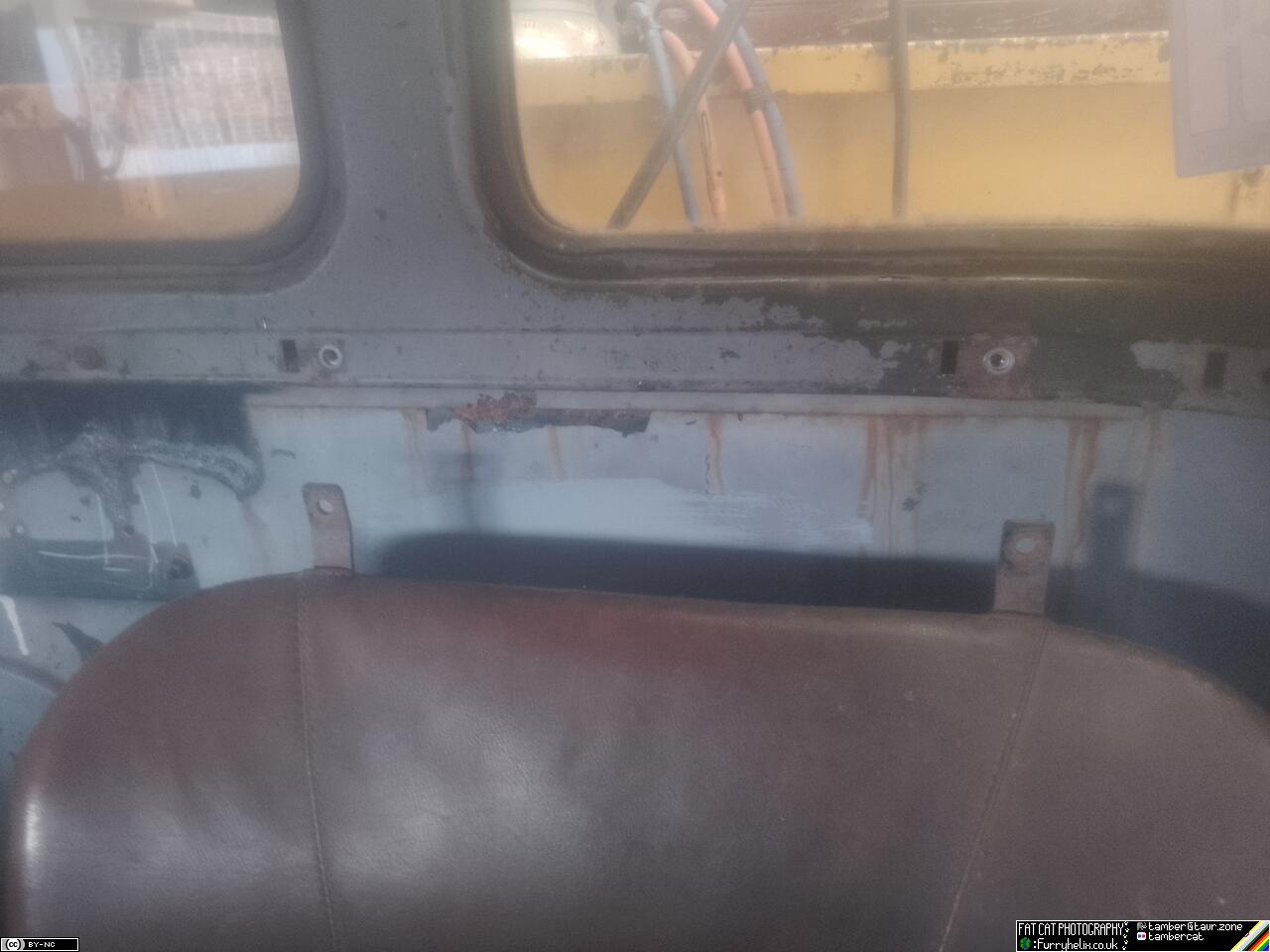 The inside back wall of the truck cab, above the passenger seat, showing two newly install thread inserts in the sheet metal bracing