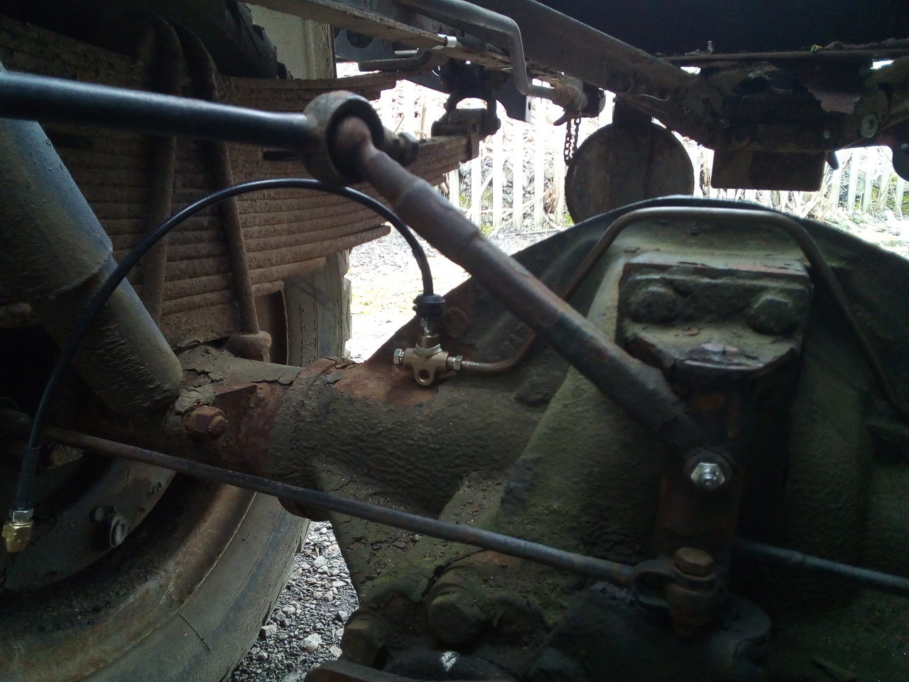 The rear axle, viewed from in front underneath the truck, now
with a flexible brake hose fitted to the top of the union, and the
previously cursed-about screwed up brake pipe removed.
