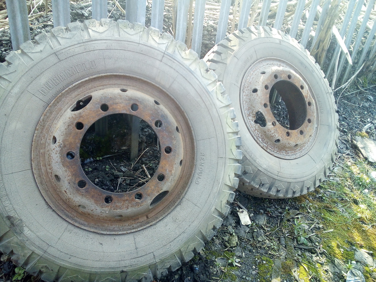 A pair of the truck's rear wheels, leaned up against the fence.