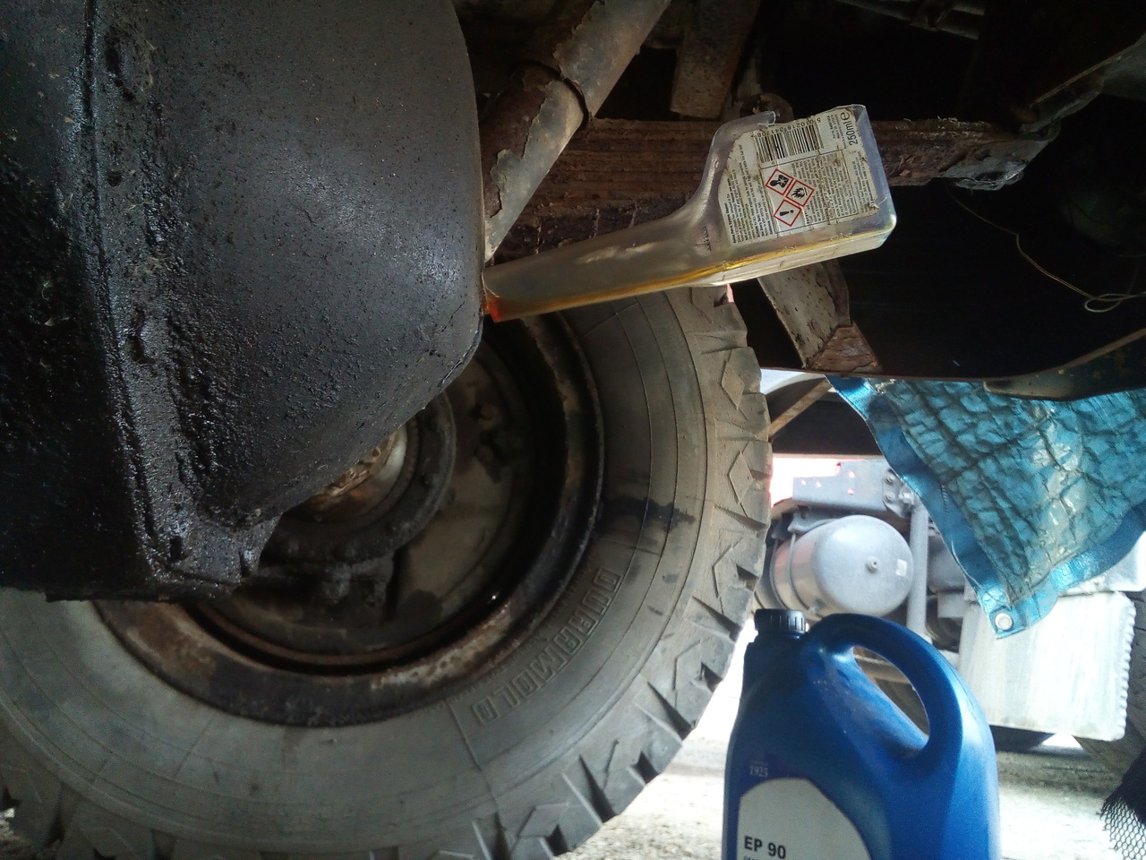 The view under the front axle of the truck, with an oddly-shaped
plastic bottle being used as a funnel to put gear oil into the front
differential.