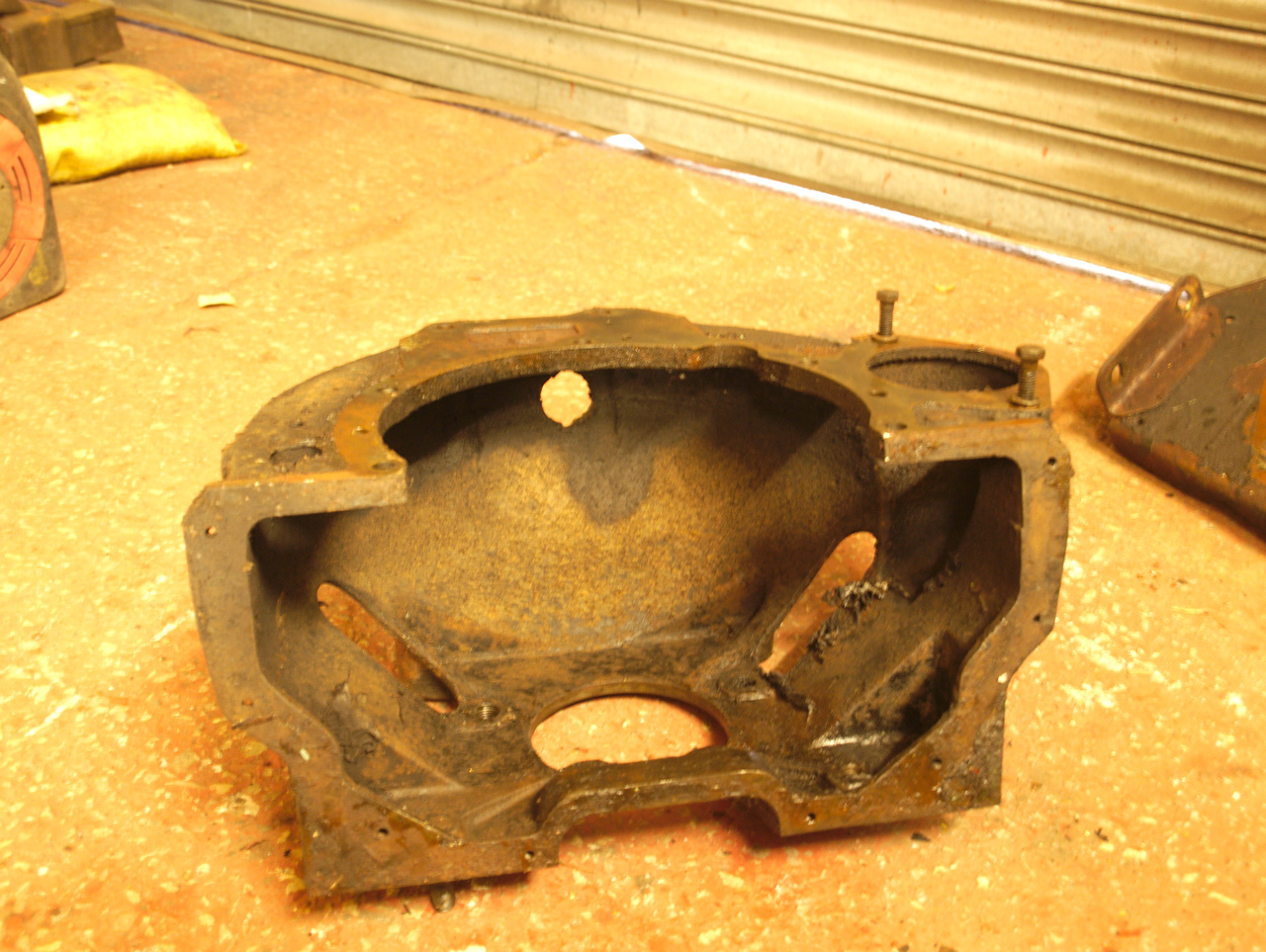 The flywheel housing on the workshop floor, tilted onto its back
to show the wide opening in the bottom for the removal of the
flywheel.