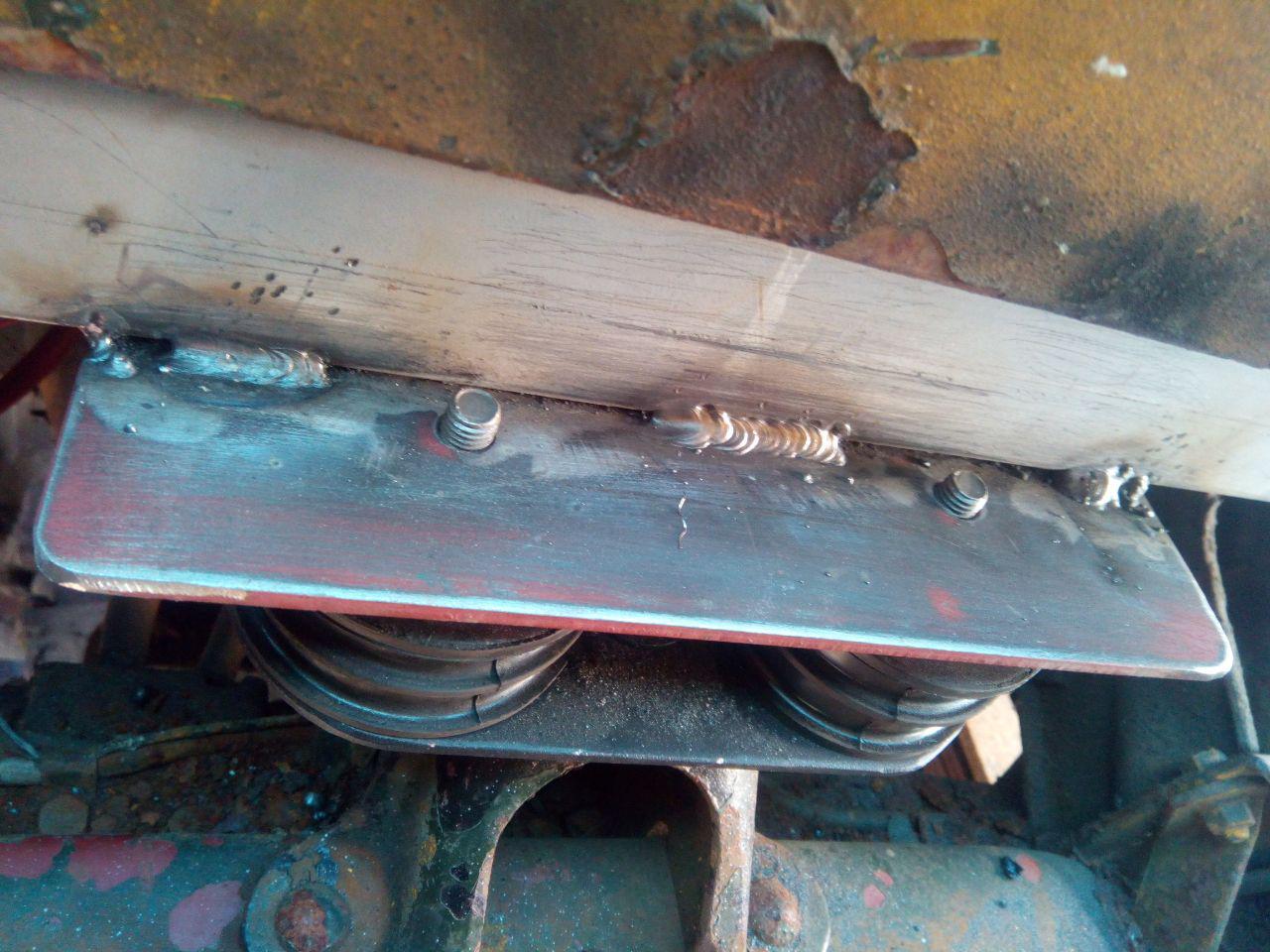 The rear bracket, now with the reinforcing tab cut off, and
welded to the cab crossmember. The studs from the rubber mounts are
protruding.