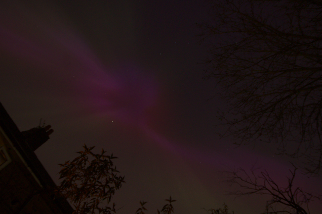 long exposure of the aurora, a deep pinkish-purple cloud with rays and streaks straying out from it