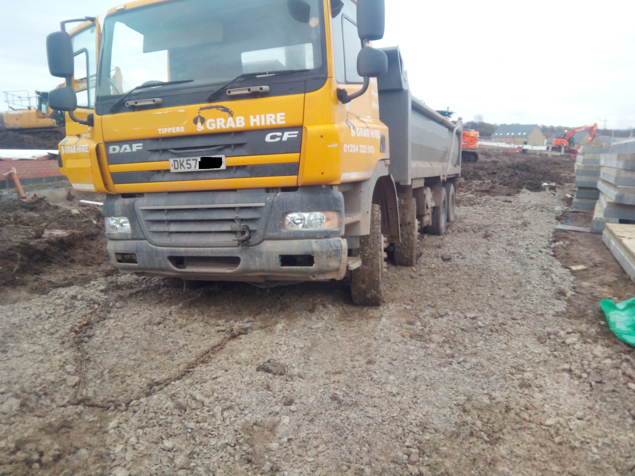 "A run-down 4-axle tipper truck, stuck in the mud."