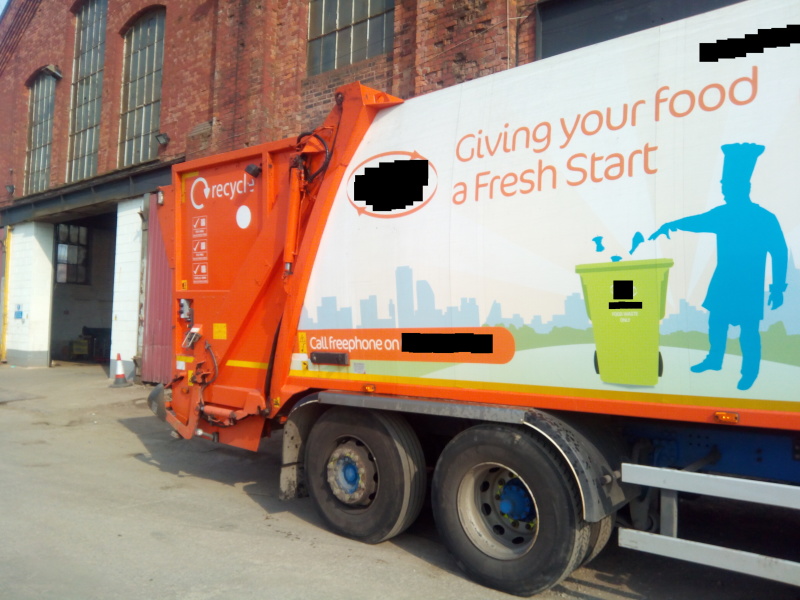 Garbage truck parked in front of workshop