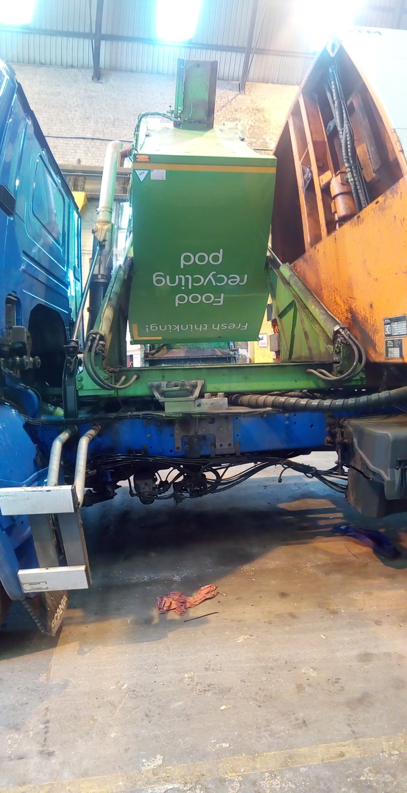 Fully-tipped truck-mounted recycling pod viewed from passenger side of truck